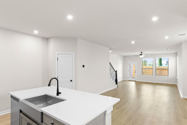 kitchen featuring ceiling fan, an island with sink, dishwasher, light hardwood / wood-style floors, and sink