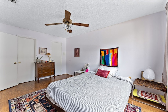 bedroom featuring ceiling fan, dark hardwood / wood-style flooring, and a textured ceiling