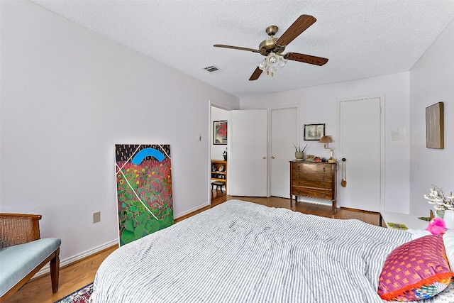 bedroom featuring ceiling fan, wood-type flooring, and a textured ceiling