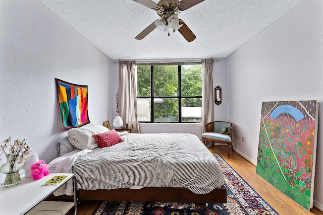 bedroom featuring ceiling fan, wood-type flooring, and a textured ceiling