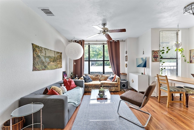 living room with a textured ceiling, hardwood / wood-style flooring, and ceiling fan