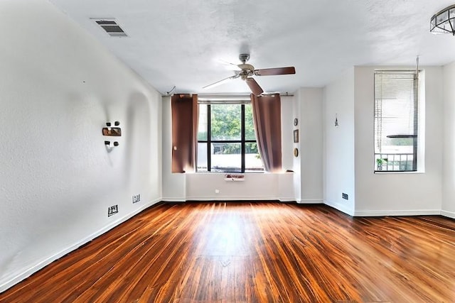 empty room featuring a textured ceiling, ceiling fan, and dark wood-type flooring