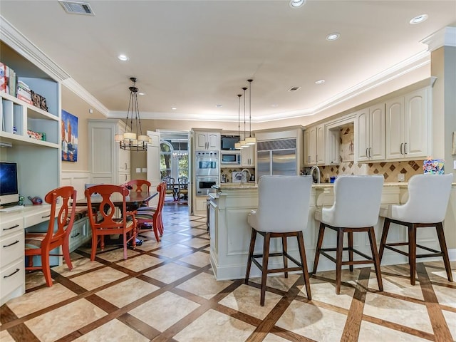 kitchen with built in appliances, a kitchen breakfast bar, sink, and hanging light fixtures