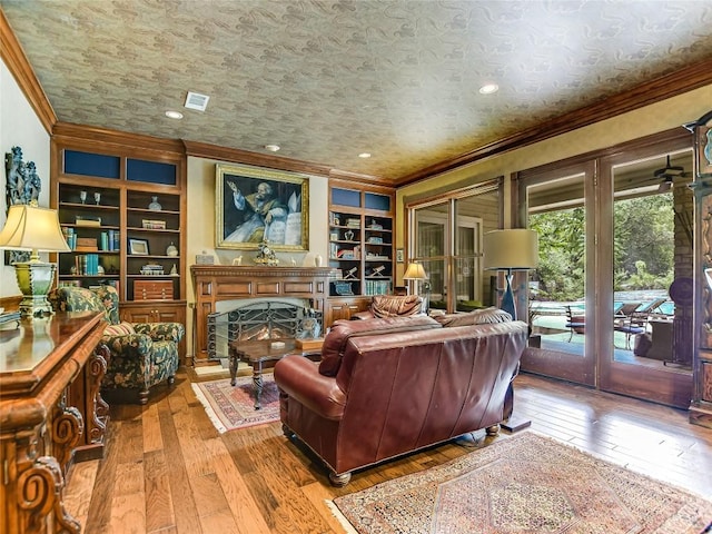 living room featuring built in features, ornamental molding, french doors, and hardwood / wood-style flooring