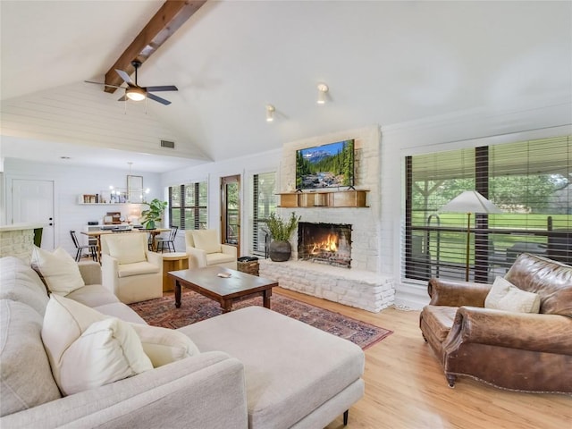 living room featuring light wood-type flooring, ceiling fan, beam ceiling, high vaulted ceiling, and a fireplace