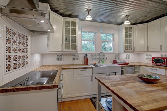 kitchen with black electric stovetop, white cabinetry, wooden counters, and sink