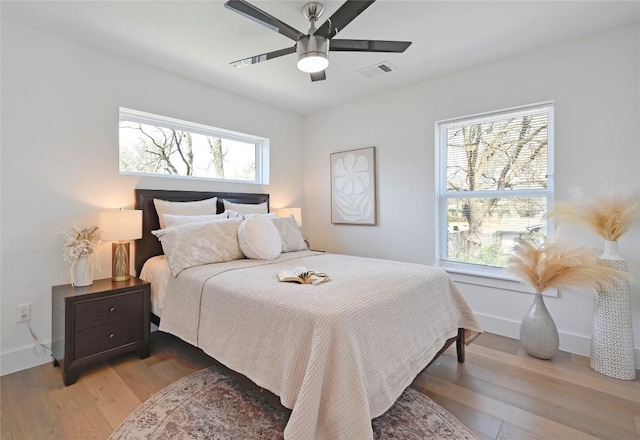 bedroom featuring multiple windows, wood finished floors, visible vents, and baseboards