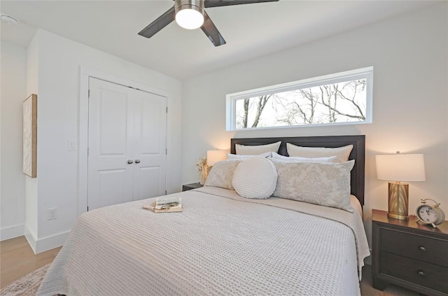 bedroom with light wood-style floors, a closet, ceiling fan, and baseboards