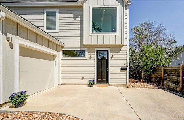 rear view of property with a garage, a shingled roof, fence, and board and batten siding