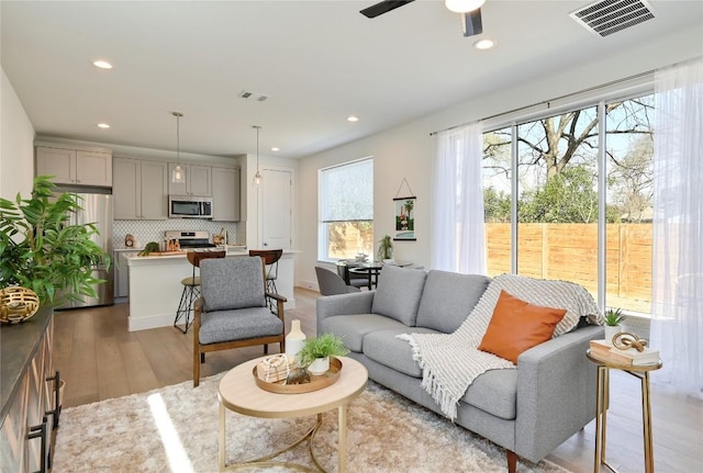 living room featuring recessed lighting, visible vents, and light wood finished floors