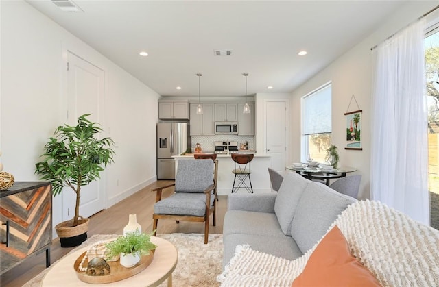 living area with recessed lighting, visible vents, and light wood-style floors