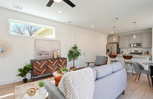 living room with light wood-type flooring, visible vents, and recessed lighting