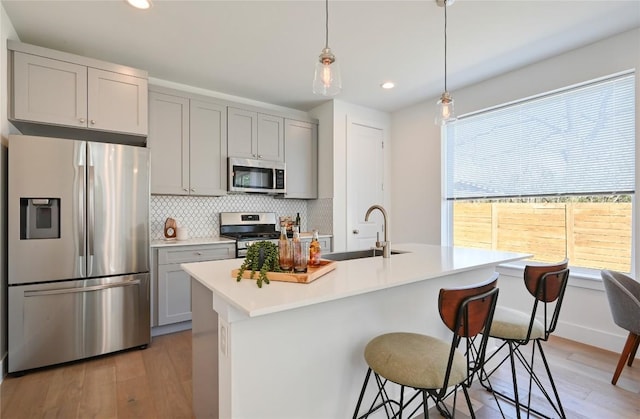 kitchen with stainless steel appliances, tasteful backsplash, a sink, and gray cabinetry