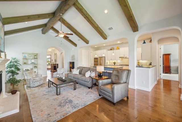 living room with ceiling fan, hardwood / wood-style floors, beamed ceiling, and high vaulted ceiling