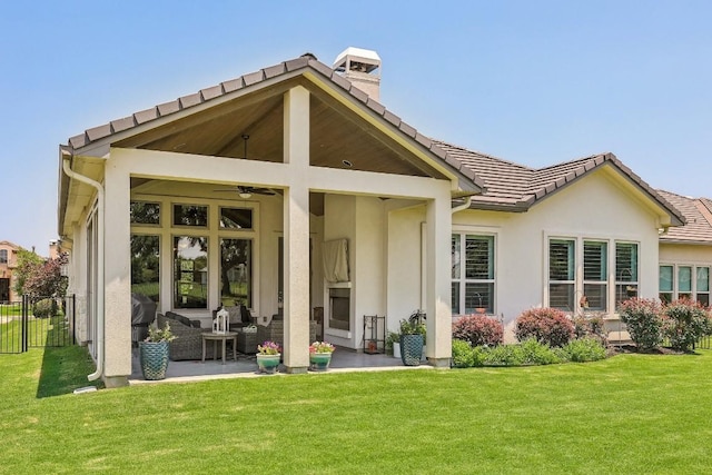 back of property with a lawn, ceiling fan, a patio, and an outdoor living space