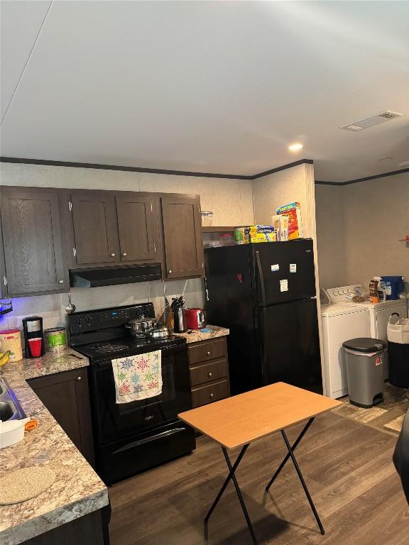 kitchen featuring black appliances, sink, light wood-type flooring, dark brown cabinetry, and washing machine and clothes dryer