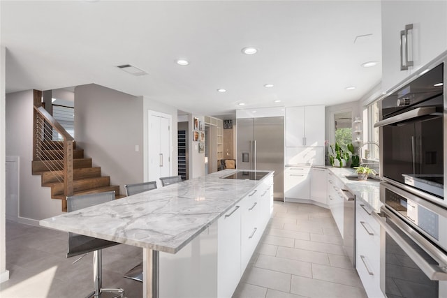 kitchen with stainless steel appliances, a breakfast bar area, white cabinets, and a spacious island