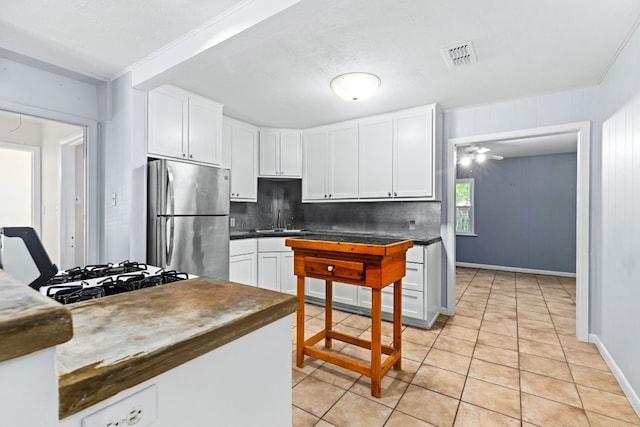 kitchen with white cabinetry, light tile patterned floors, gas cooktop, stainless steel fridge, and backsplash