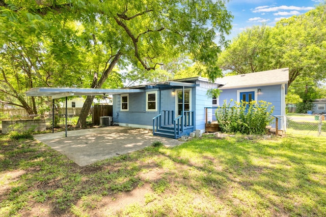 rear view of property with a yard, central AC unit, and a patio area