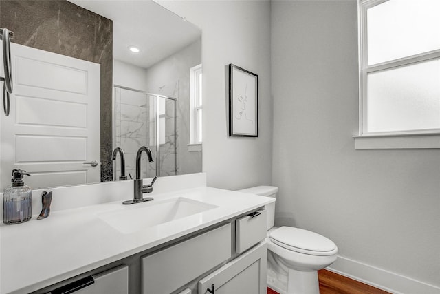 bathroom featuring toilet, hardwood / wood-style flooring, a shower with shower door, and vanity