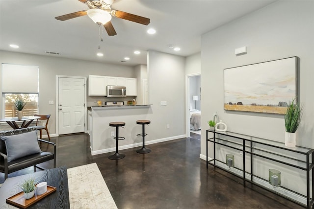 interior space featuring white cabinetry, a breakfast bar, ceiling fan, and kitchen peninsula