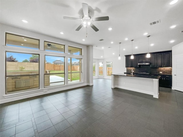 kitchen with decorative light fixtures, ceiling fan, dark tile patterned floors, and tasteful backsplash