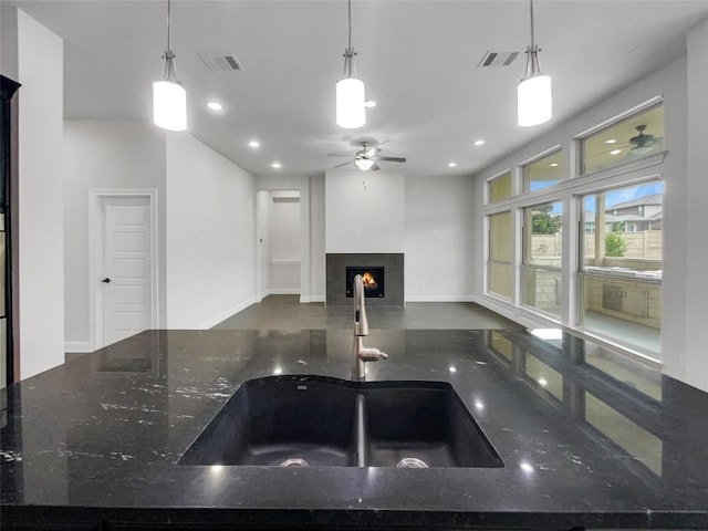 kitchen featuring hanging light fixtures, dark stone counters, and sink