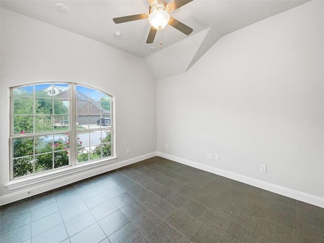 empty room with ceiling fan, dark tile patterned floors, and vaulted ceiling