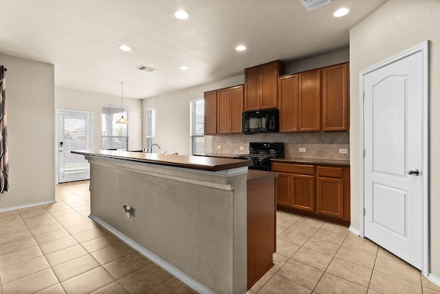 kitchen with black appliances, light tile patterned floors, pendant lighting, decorative backsplash, and an island with sink