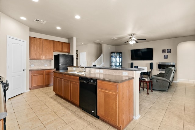 kitchen with a kitchen island with sink, black appliances, sink, and light tile patterned flooring