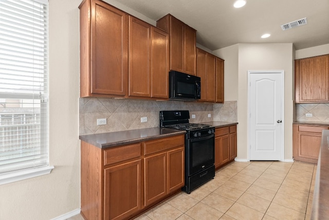 kitchen featuring backsplash, a healthy amount of sunlight, light tile patterned floors, and black appliances