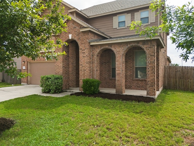 traditional-style house with concrete driveway, fence, a front lawn, brick siding, and a garage