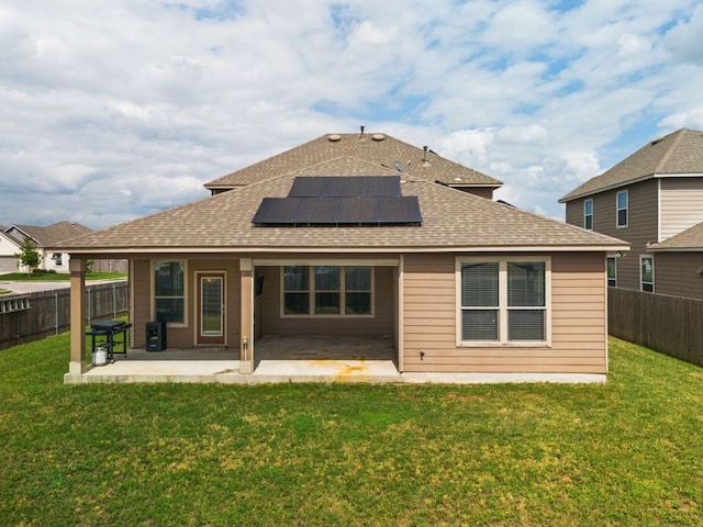 rear view of house with solar panels, a yard, and a patio area