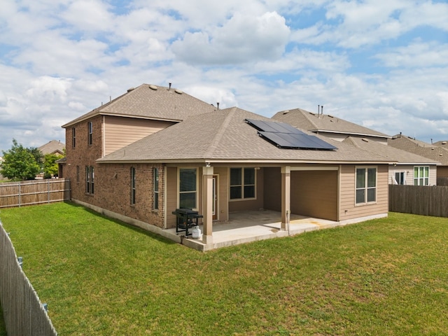 rear view of house with solar panels, a yard, and a patio area