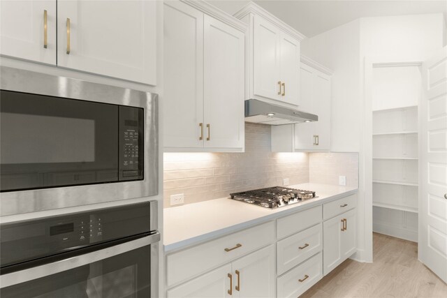 kitchen with white cabinetry, light hardwood / wood-style floors, appliances with stainless steel finishes, and backsplash