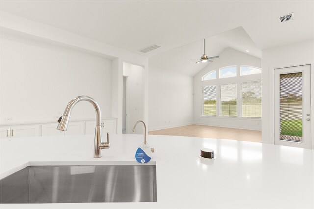 kitchen with lofted ceiling, sink, white cabinetry, and ceiling fan