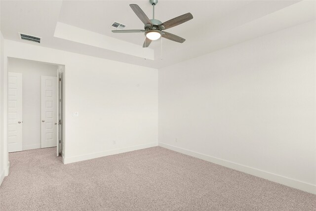 spare room with light carpet, a raised ceiling, and ceiling fan