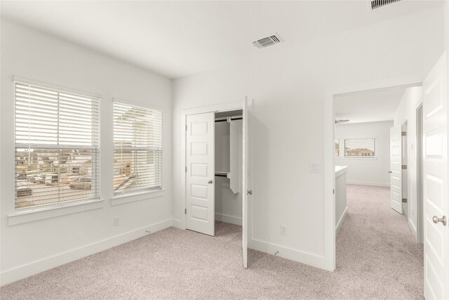 unfurnished bedroom featuring a closet and light colored carpet