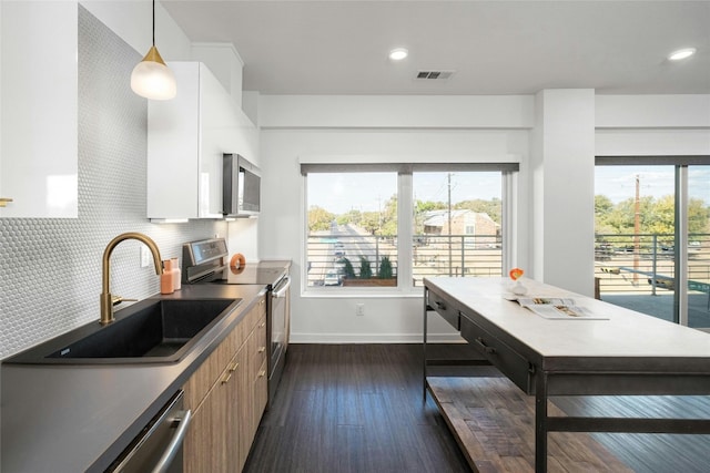 kitchen with stainless steel appliances, sink, white cabinetry, tasteful backsplash, and pendant lighting