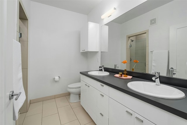 bathroom with toilet, a tile shower, tile patterned floors, and vanity