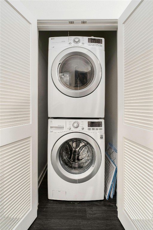 laundry room with stacked washer and clothes dryer and dark hardwood / wood-style floors