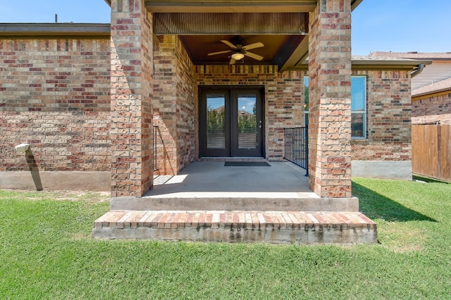 property entrance with ceiling fan, a lawn, and french doors