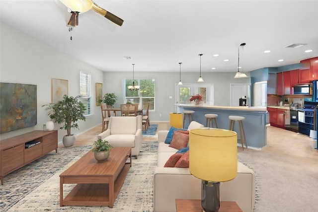 carpeted living room with ceiling fan with notable chandelier