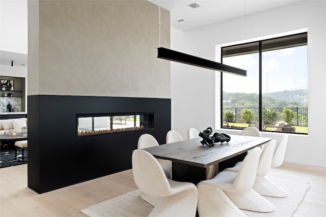 dining space featuring a multi sided fireplace and light wood-type flooring