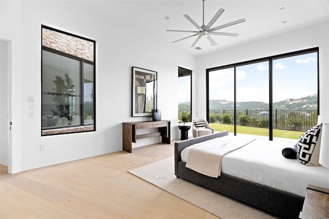 bedroom featuring access to exterior, a mountain view, light wood-type flooring, and ceiling fan