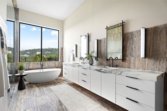 bathroom featuring vanity, a bathtub, and tile walls