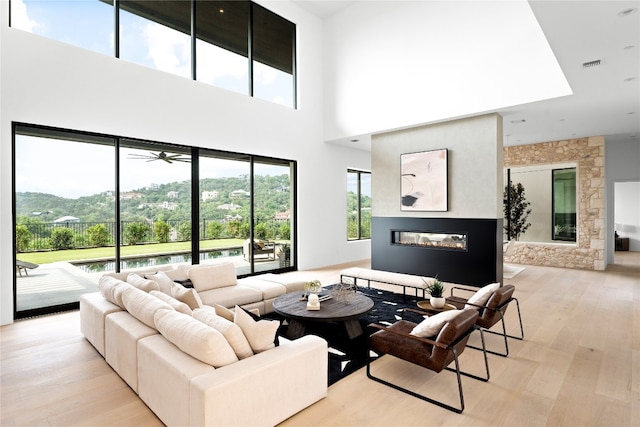 living room with a towering ceiling, light hardwood / wood-style floors, and ceiling fan