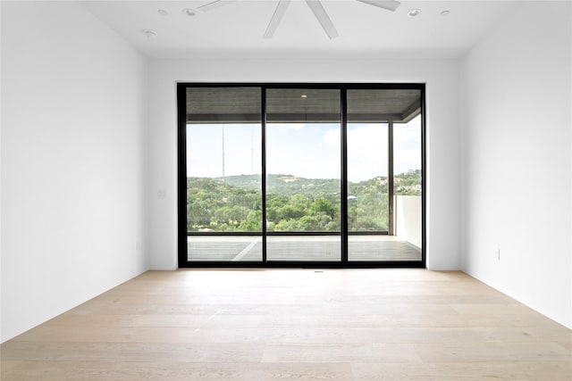 spare room featuring a mountain view, light hardwood / wood-style flooring, and ceiling fan