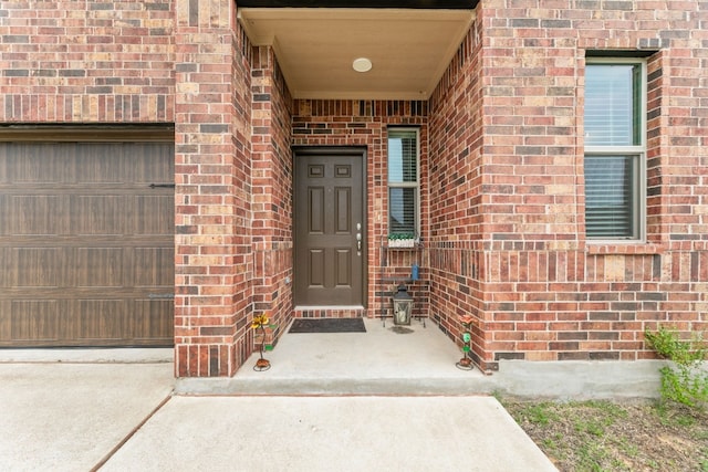 property entrance featuring a garage and brick siding