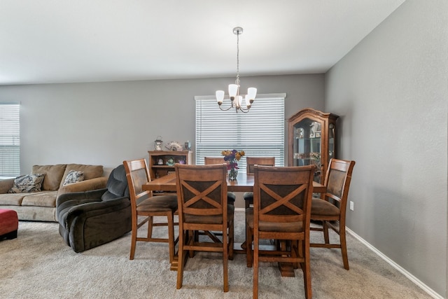 dining space with a chandelier, baseboards, and light colored carpet